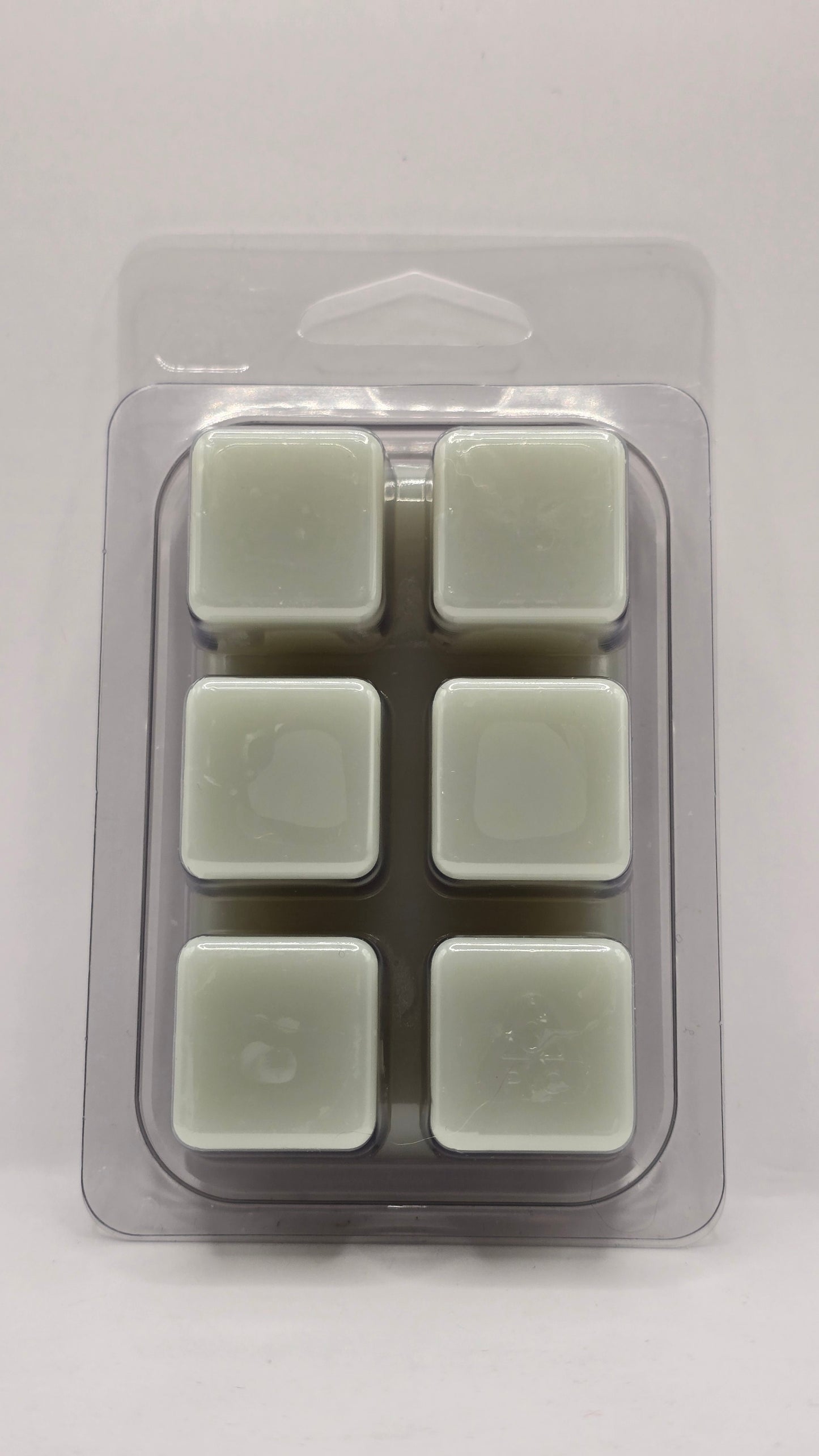 Back view of Blue Sage and Sea Salt Wax Melt clamshell packaging by CORGI CANDLE. Clear plastic wax melt container showing soy wax cubes with black and white label visible through the back.