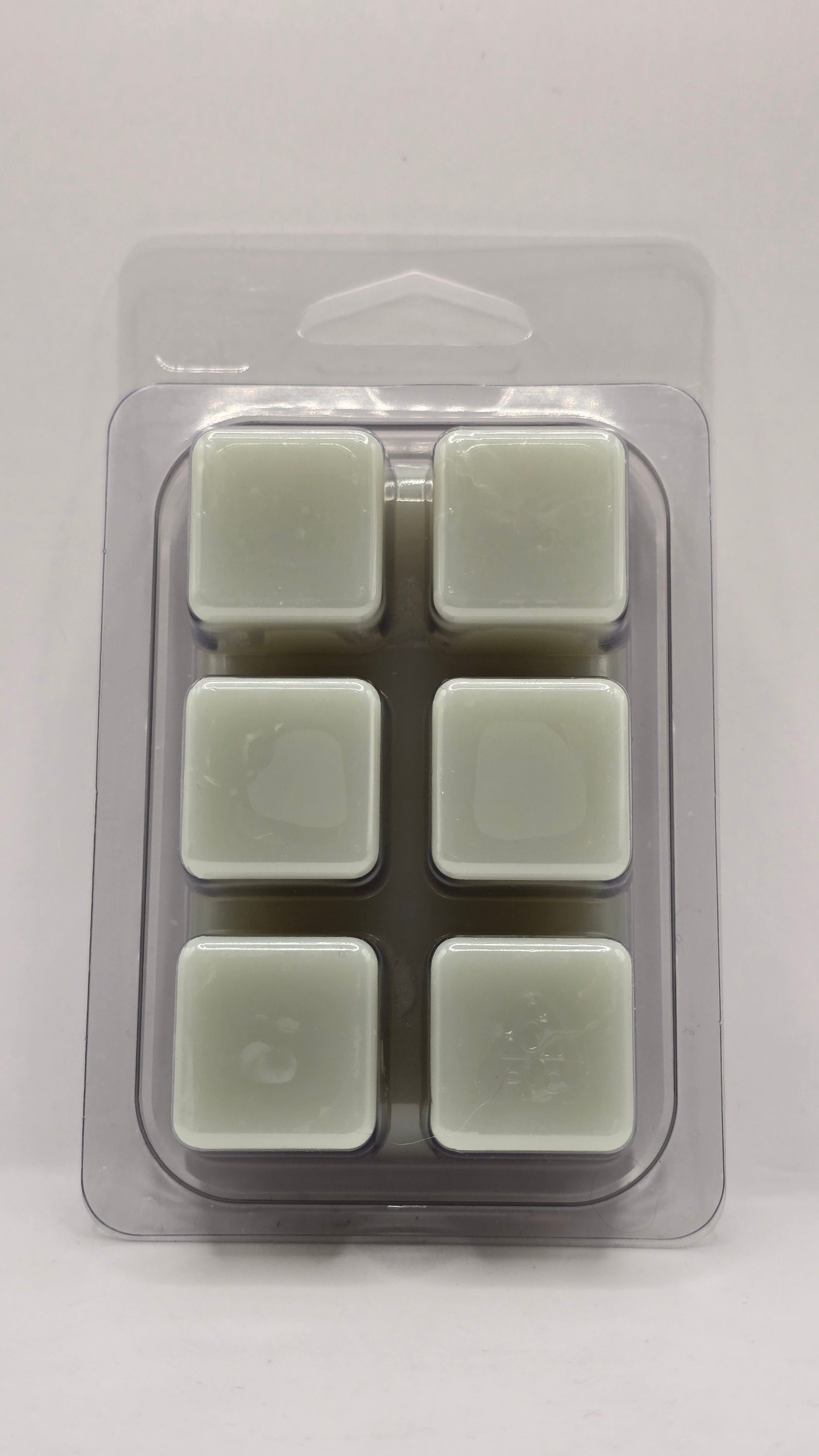 Back view of Blue Sage and Sea Salt Wax Melt clamshell packaging by CORGI CANDLE. Clear plastic wax melt container showing soy wax cubes with black and white label visible through the back.