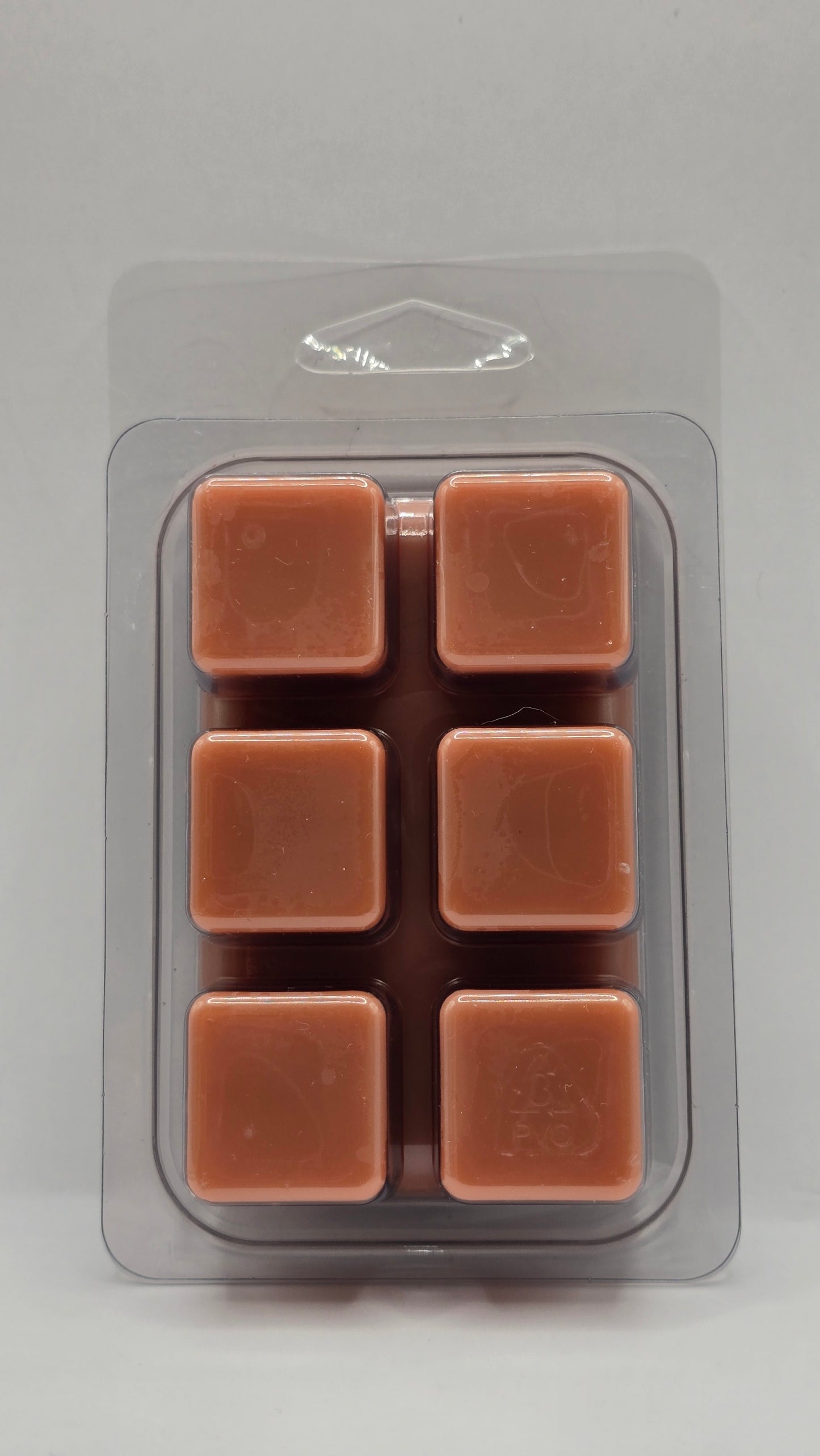 Pack of six brown wax melts in a clear plastic packaging on a gray background