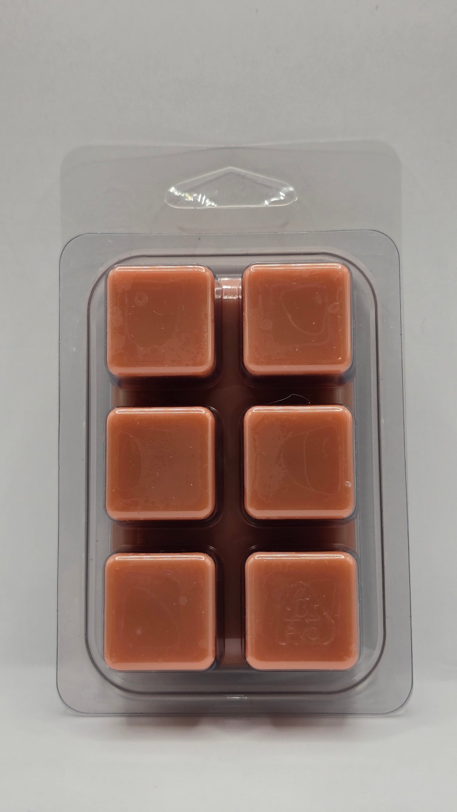 Pack of six brown wax melts in a clear plastic packaging on a gray background