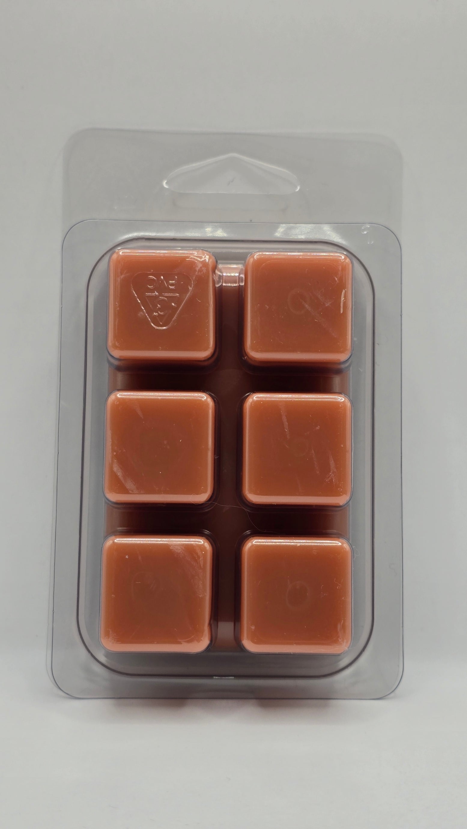Six brown wax melts in a clear plastic packaging on a light gray background