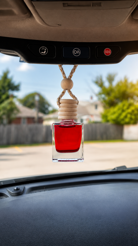 CORGI CANDLE hanging car diffuser with red fragrance oil attached to a rearview mirror inside a vehicle.